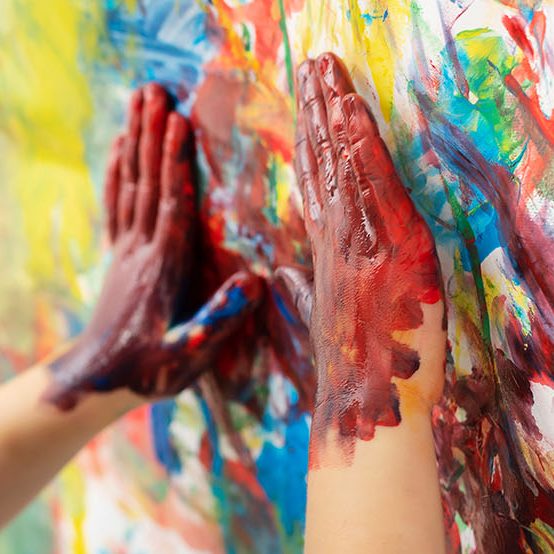 Kinderhände mit bunter Farbe auf Papier