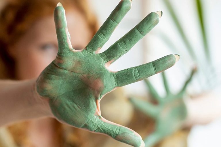 Handflächen mit grüner Farbe beschmiert