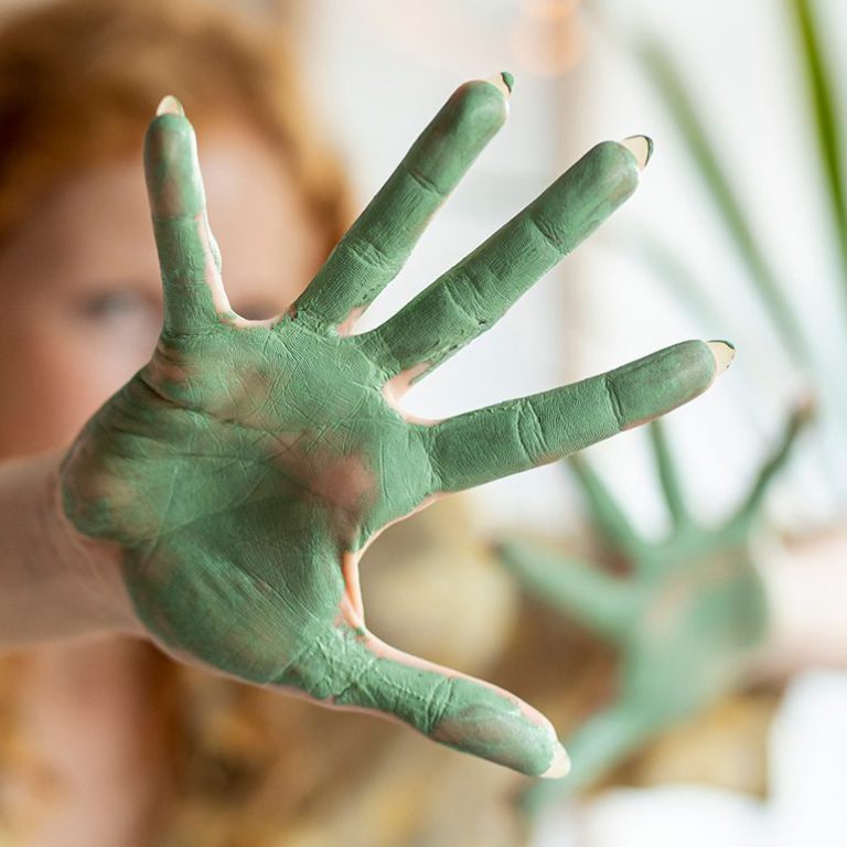 Hände mit grüner Farbe beschmiert